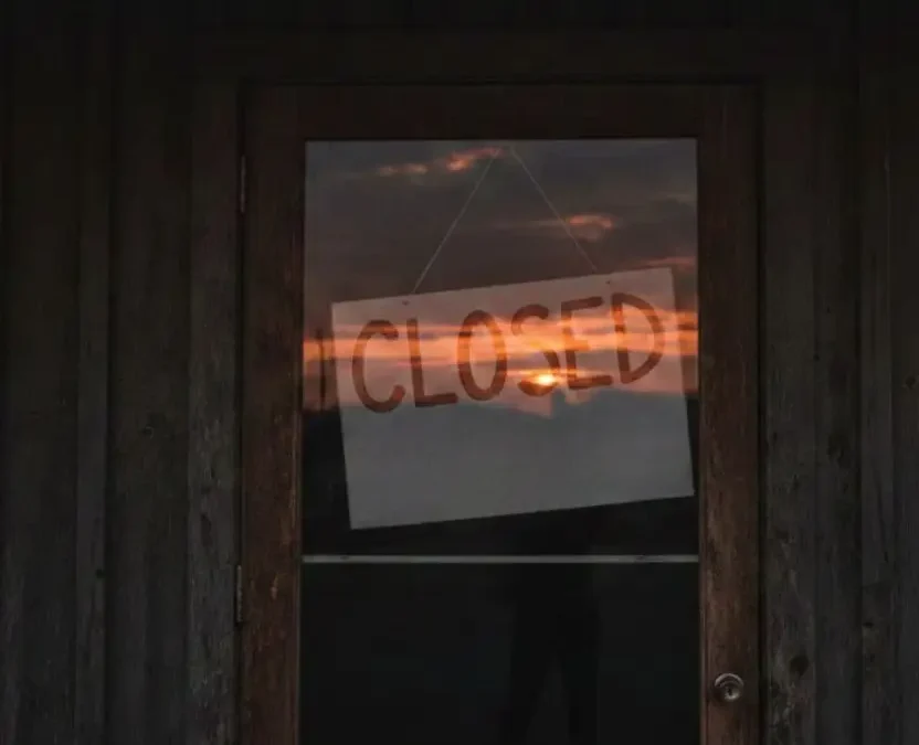 A "Closed" sign hanging on the weathered wooden door of a Waco BBQ restaurant