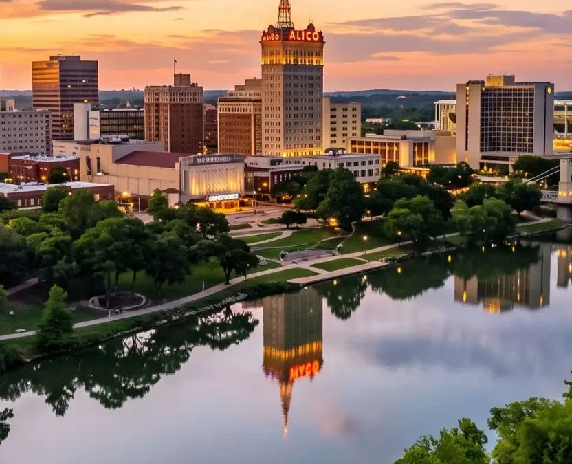 Aerial drone view of the Waco Texas downtown skyline and ALICO building reflected in the Brazos River at sunset, showcasing romantic lodging locations and the best places to stay for couples in Waco Texas.